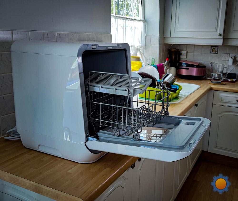 comfee miniplus smart dishwasher with its door open sitting on a kitchen countertop