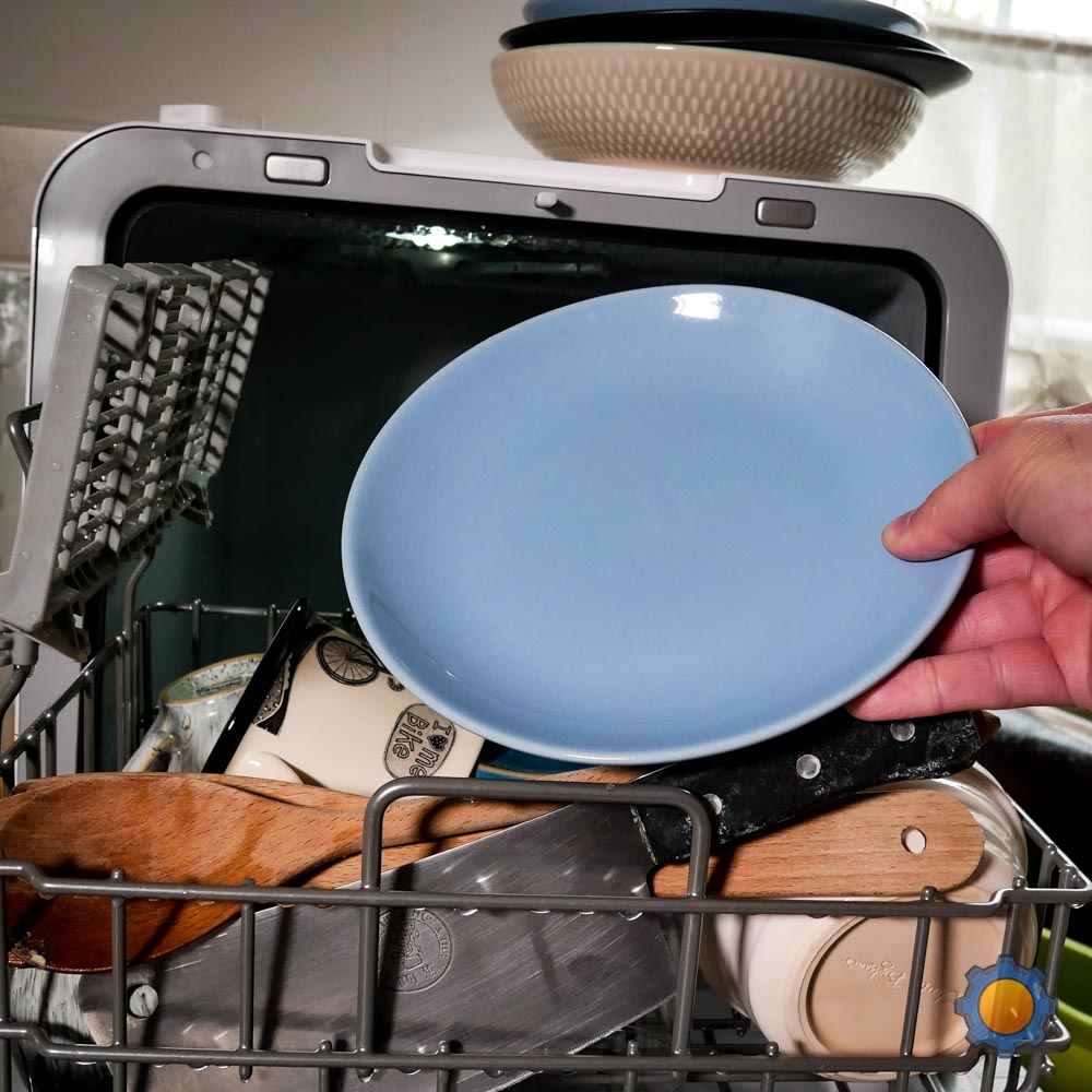 hand holding clean blue bowl in front of the comfee miniplus smart dishwasher